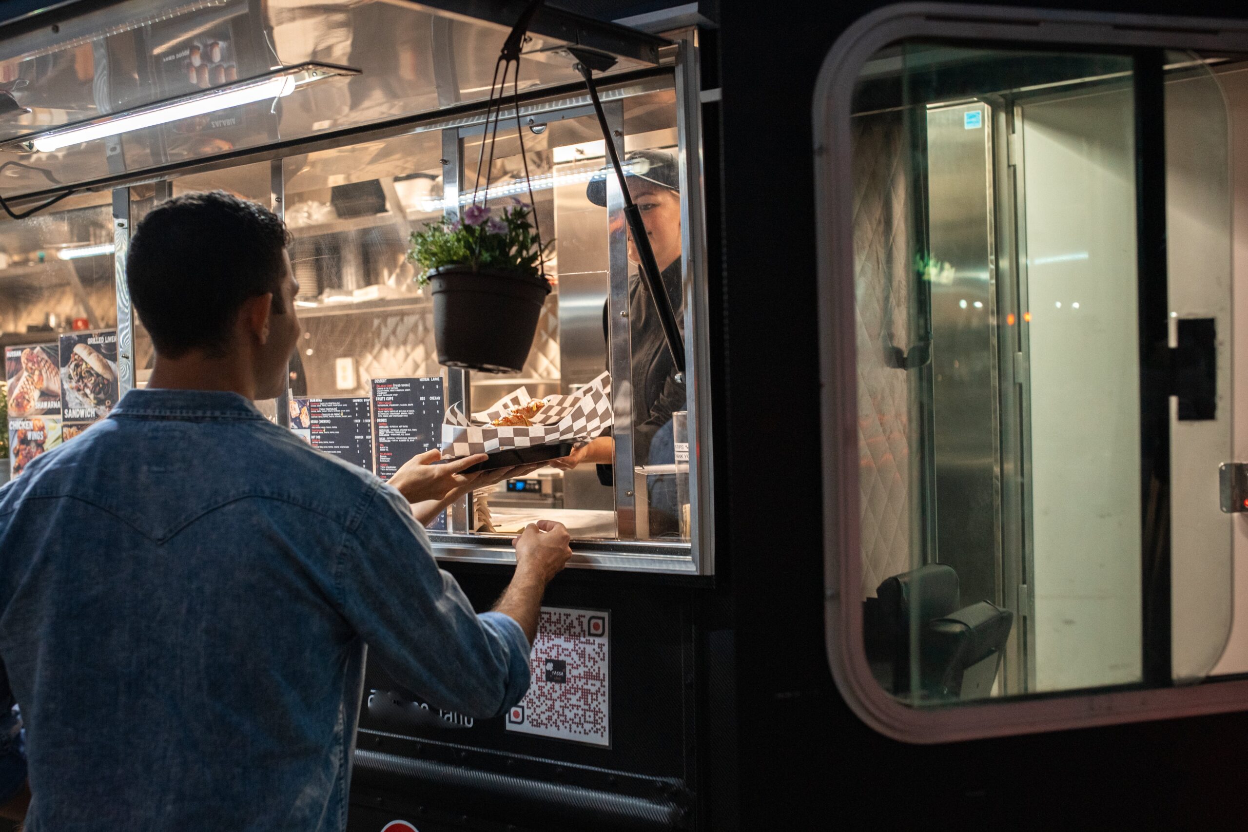 A man handing another food from his food truck